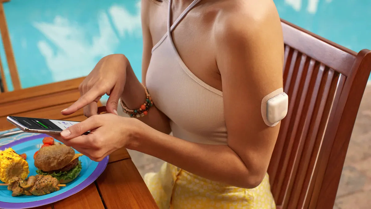 Persoon met Omnipod 5 insulinepod op bovenarm tijdens maaltijd